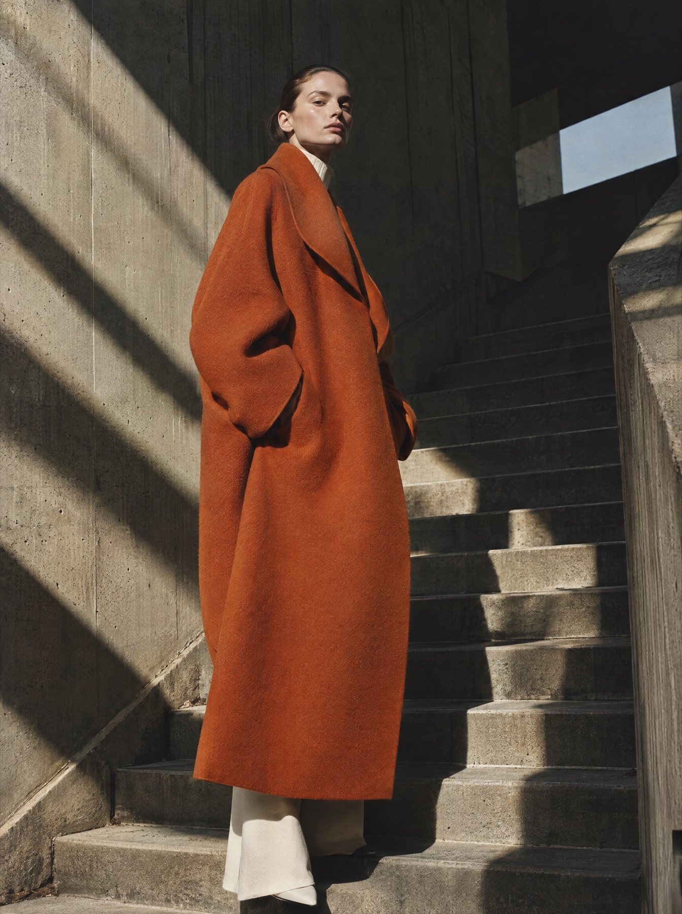 Model in a rust coat on concrete stairs